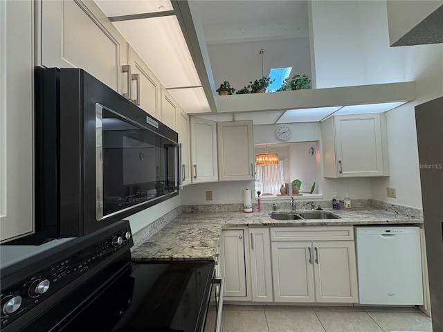 kitchen featuring black appliances, a sink, light tile patterned floors, light stone countertops, and a towering ceiling