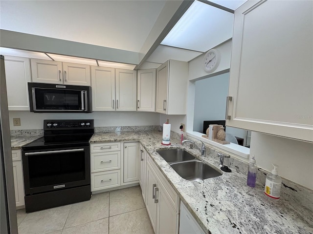 kitchen featuring black appliances, light tile patterned floors, light stone countertops, and a sink