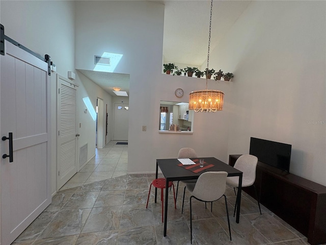 dining space with baseboards, visible vents, a towering ceiling, a barn door, and a chandelier