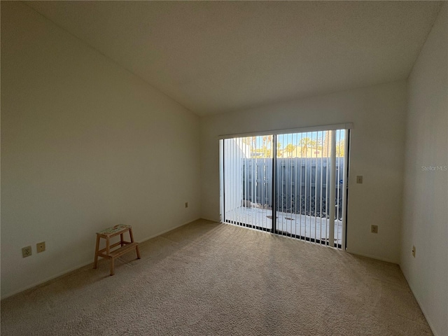 carpeted spare room featuring vaulted ceiling