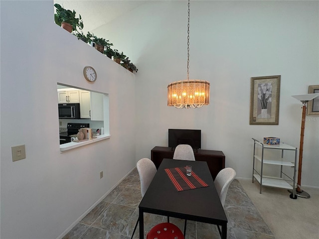 carpeted dining room featuring baseboards, a high ceiling, and an inviting chandelier