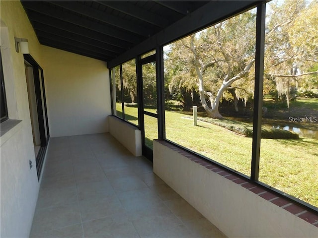 sunroom featuring lofted ceiling with beams and a water view