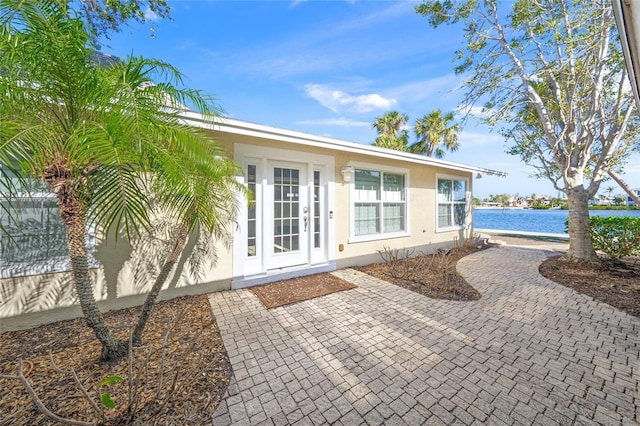 view of exterior entry featuring a water view and a patio