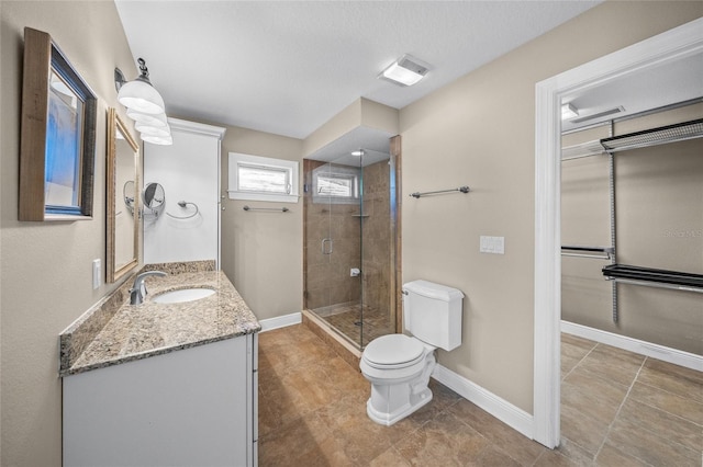 bathroom with toilet, a textured ceiling, walk in shower, and vanity