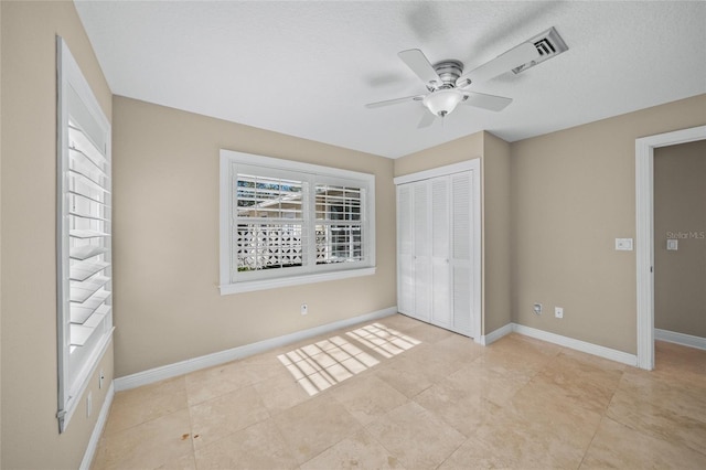 unfurnished bedroom with a textured ceiling, ceiling fan, light tile patterned flooring, and a closet