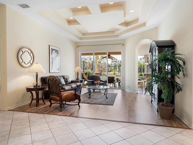 living room with a tray ceiling and light wood-type flooring