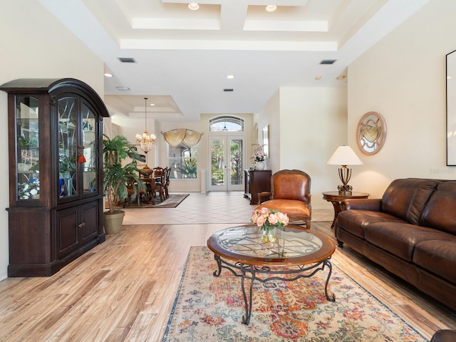 living room featuring a notable chandelier, light hardwood / wood-style flooring, and a raised ceiling