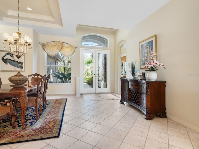 entryway featuring a notable chandelier, french doors, a raised ceiling, and light tile patterned floors