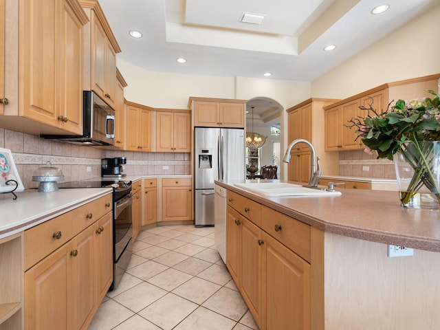 kitchen featuring stainless steel appliances, sink, a raised ceiling, and light brown cabinets