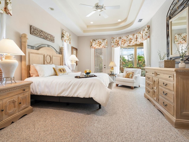 bedroom featuring ceiling fan, a tray ceiling, and light colored carpet