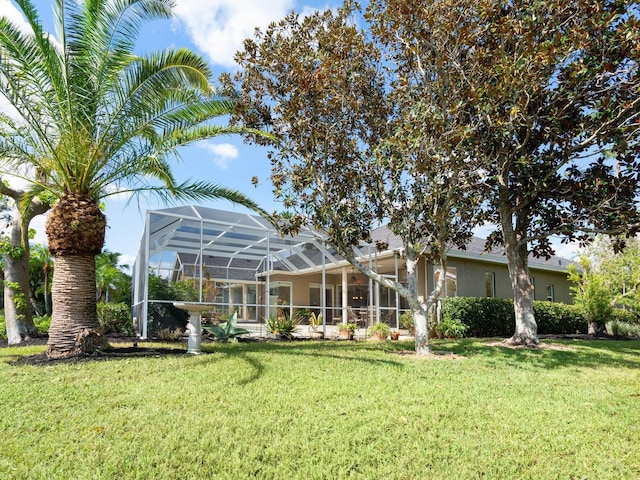 rear view of property featuring a lanai and a lawn