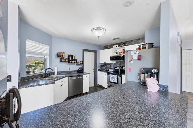 kitchen featuring tasteful backsplash, sink, white cabinetry, stainless steel appliances, and dark wood-type flooring