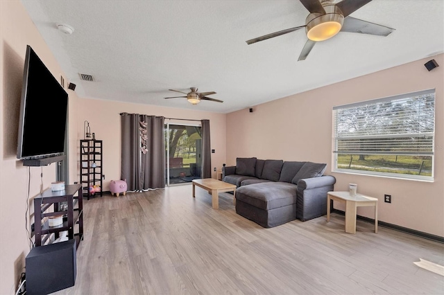 living room featuring a textured ceiling, a healthy amount of sunlight, light wood-type flooring, and ceiling fan