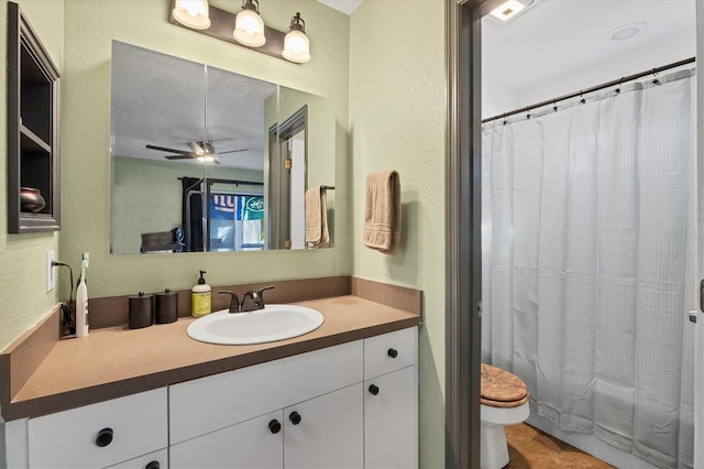 bathroom featuring a textured ceiling, a shower with shower curtain, toilet, ceiling fan, and vanity