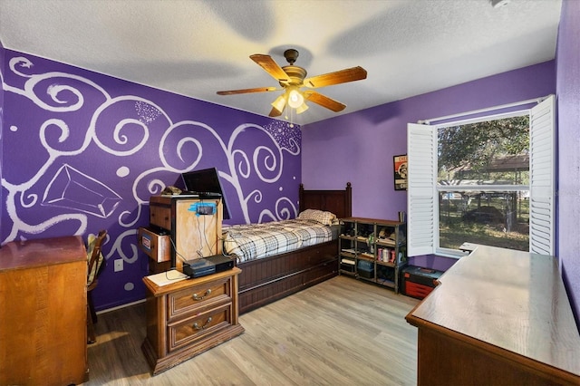 bedroom with a textured ceiling, hardwood / wood-style flooring, and ceiling fan