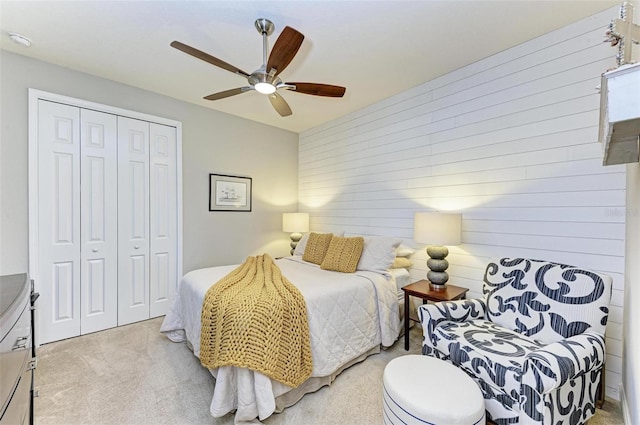 carpeted bedroom with a closet, ceiling fan, and wood walls