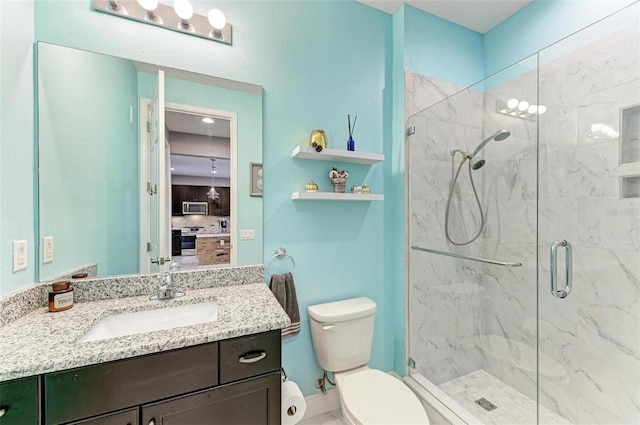 bathroom featuring a shower with door, vanity, and toilet