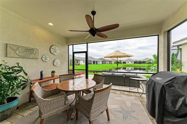 sunroom featuring a water view and ceiling fan