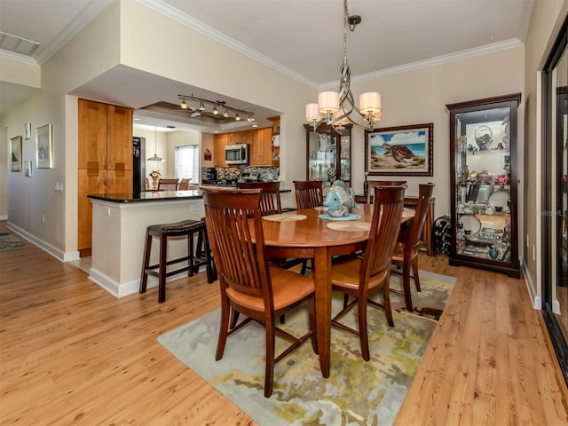 dining room with ornamental molding and light hardwood / wood-style flooring