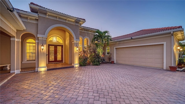 exterior entry at dusk with french doors and a garage