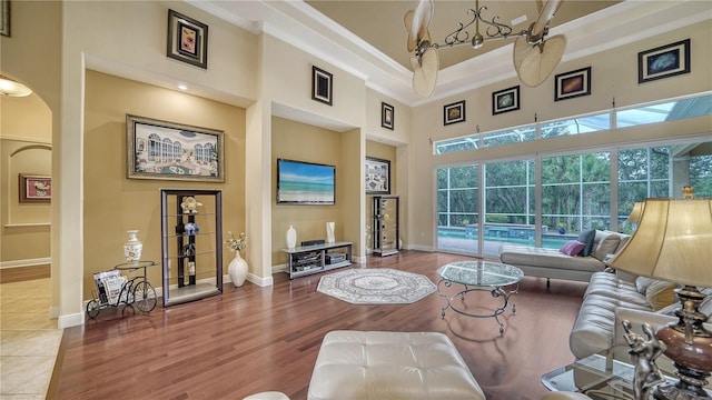 living room featuring hardwood / wood-style floors, a towering ceiling, ceiling fan, and crown molding