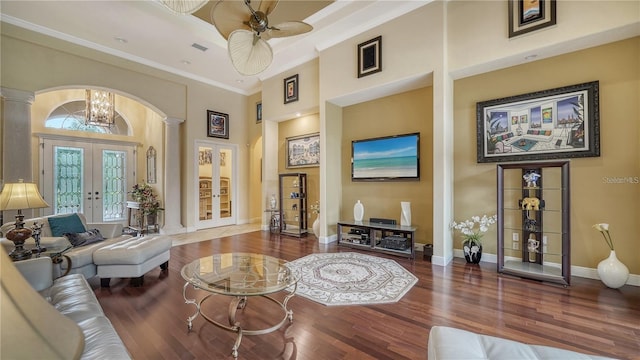 living room featuring hardwood / wood-style floors, a high ceiling, french doors, ceiling fan with notable chandelier, and ornamental molding