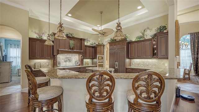 kitchen with built in appliances, decorative light fixtures, dark hardwood / wood-style flooring, and a breakfast bar area