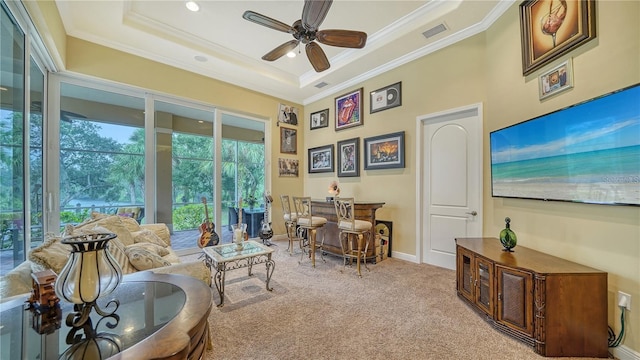 carpeted living room featuring a raised ceiling, ceiling fan, and crown molding