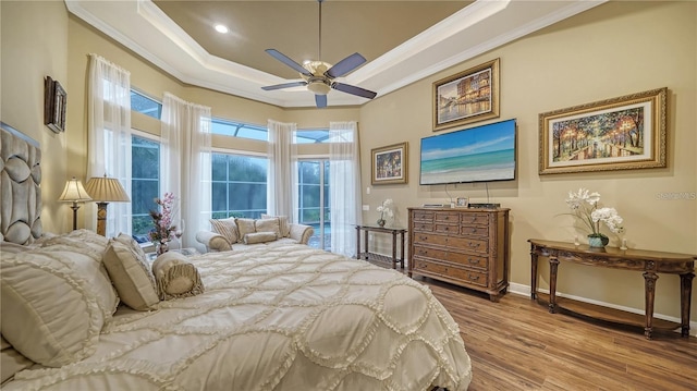 bedroom with a tray ceiling, ceiling fan, ornamental molding, and hardwood / wood-style flooring