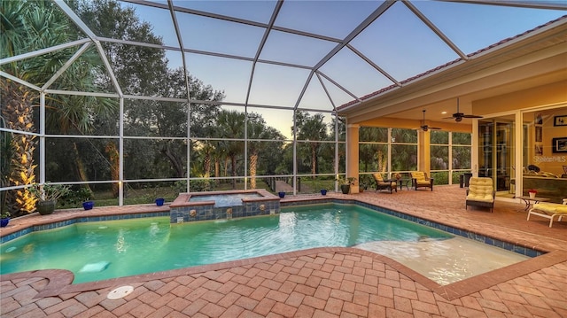 pool at dusk featuring a lanai, a patio area, an in ground hot tub, and ceiling fan