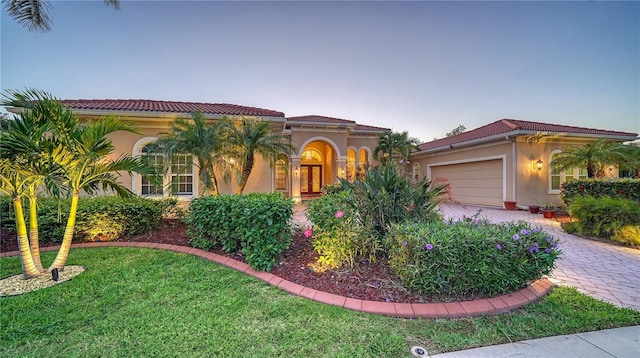 mediterranean / spanish home with a garage and a lawn