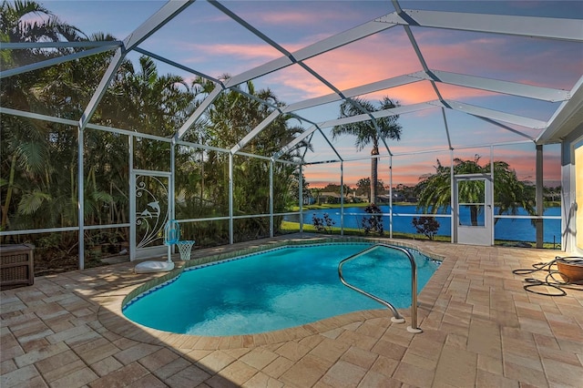 pool at dusk featuring a water view, glass enclosure, and a patio area