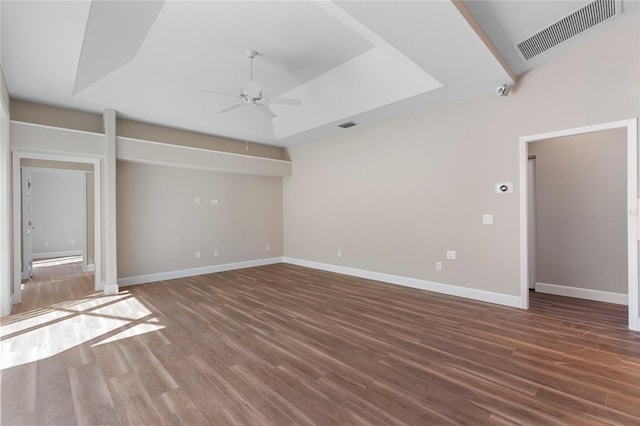 unfurnished living room with a tray ceiling, ceiling fan, and dark hardwood / wood-style floors