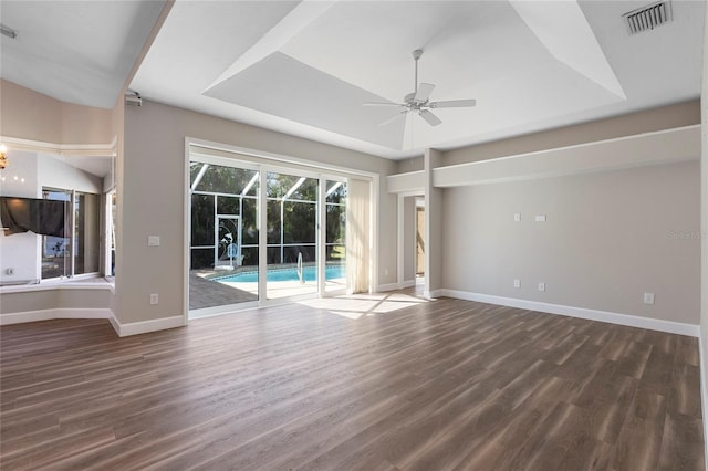 unfurnished living room with a tray ceiling, ceiling fan, and dark wood-type flooring