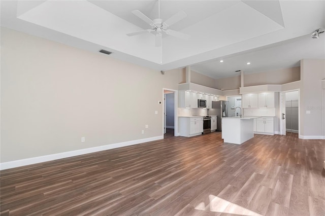 kitchen featuring a kitchen island with sink, a high ceiling, ceiling fan, appliances with stainless steel finishes, and white cabinetry