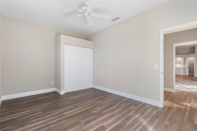 unfurnished bedroom with ceiling fan, a closet, and dark wood-type flooring