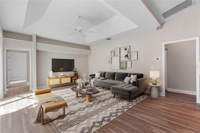 living room with hardwood / wood-style floors, ceiling fan, and a tray ceiling