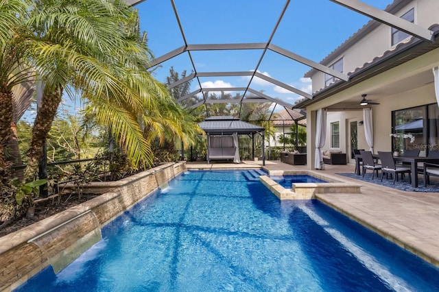 view of swimming pool with an in ground hot tub, pool water feature, a lanai, ceiling fan, and a patio area