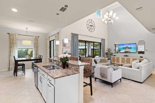 kitchen featuring decorative light fixtures, sink, white cabinets, a notable chandelier, and light stone countertops