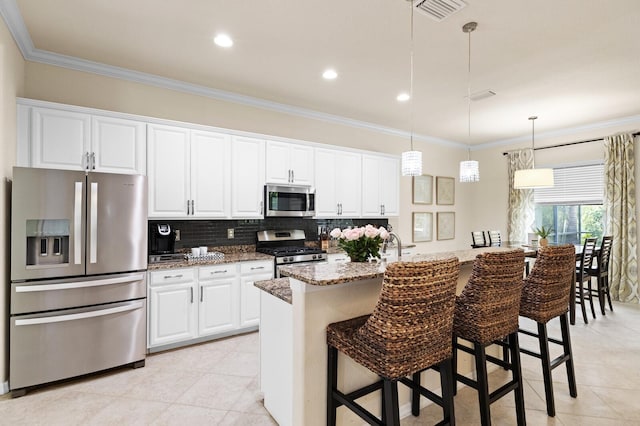 kitchen with white cabinetry, stainless steel appliances, a kitchen bar, and light stone countertops