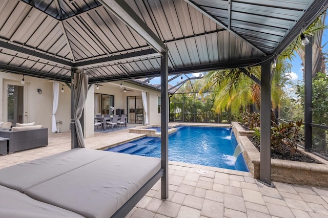 view of swimming pool with pool water feature, a lanai, outdoor lounge area, ceiling fan, and a patio