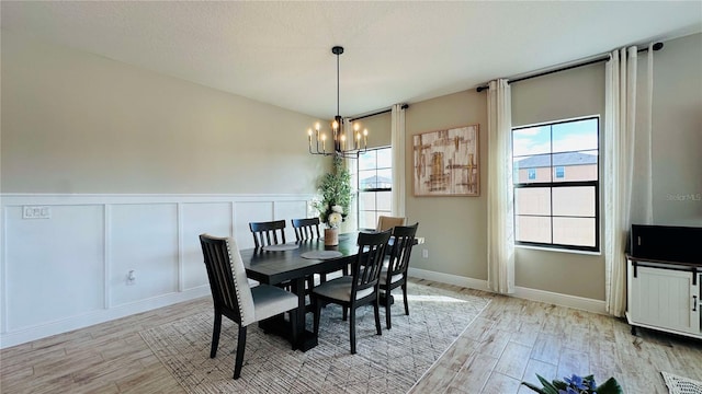 dining room featuring a textured ceiling, a chandelier, and light hardwood / wood-style flooring