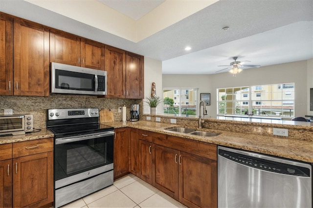 kitchen featuring light stone counters, stainless steel appliances, tasteful backsplash, and sink