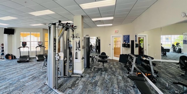 workout area with dark colored carpet and a paneled ceiling