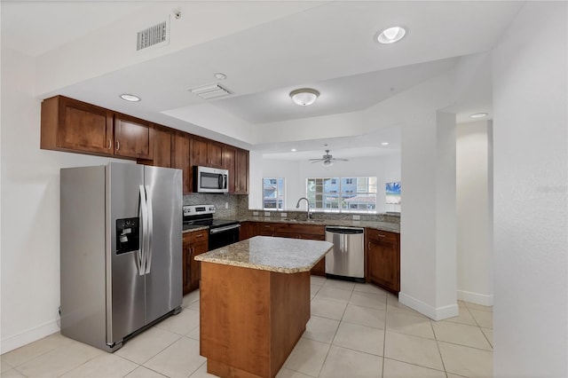 14041 Bellagio Way Unit 214, Osprey, FL 34229 - kitchen with backsplash, appliances with stainless steel finishes, a kitchen island, and visible vents