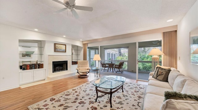 living room featuring ceiling fan, hardwood / wood-style flooring, and a textured ceiling