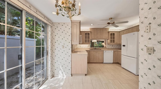 kitchen with light brown cabinets, hanging light fixtures, ceiling fan with notable chandelier, sink, and white appliances