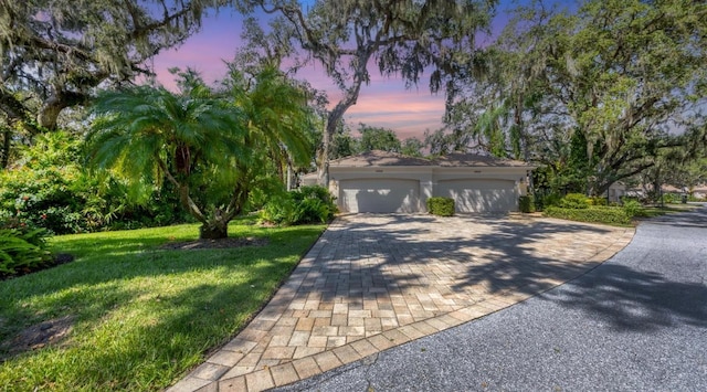 view of front of home with a garage and a lawn