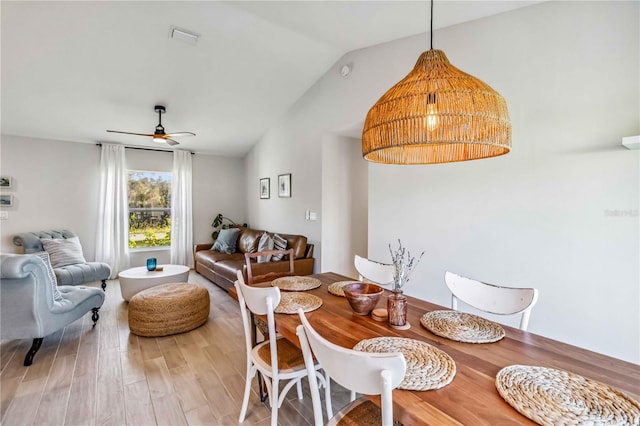 dining room with ceiling fan, vaulted ceiling, and hardwood / wood-style floors