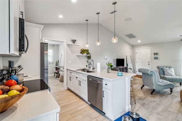 kitchen with hanging light fixtures, white cabinetry, light hardwood / wood-style floors, stainless steel appliances, and vaulted ceiling